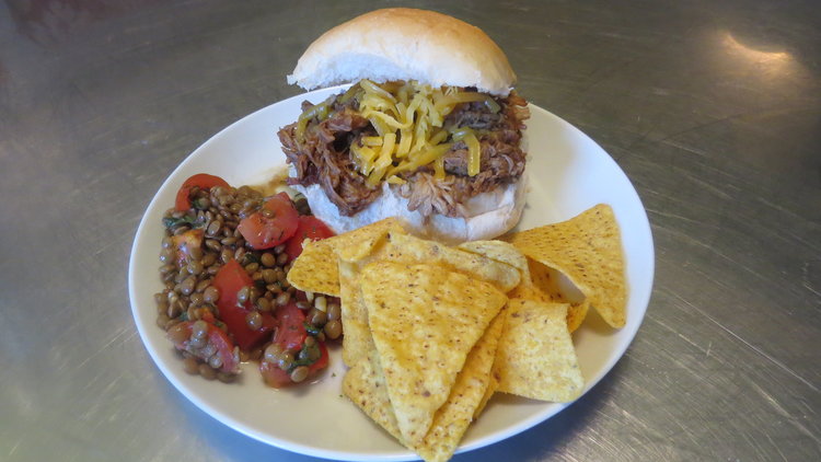 Pulled pork on a roll with a lentil and tomato salad.